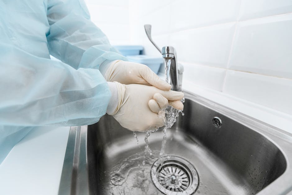 medical professional washing hands under running water to en